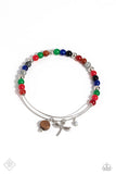 A charismatic collection of multicolored stone beads is threaded along a skinny silver wire, as it curls into a dainty bangle. Silver beads are mixed along the colorful display, adding hints of metallic sheen, as a wooden disc, a singular white stone bead, and a silver dragonfly charm slide and sway in a whimsical finish.  Sold as one individual bracelet.