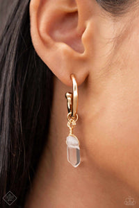 A small, skinny, gold hoop curves around the ear in a timeless fashion. A gold ball is affixed to the end of the hoop, reminiscent of a barbell fitting. Delicately attached to gold wire, a chiseled piece of clear white stone slides along the curvature of the hoop, adding a surprising hint of stony movement.