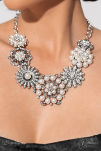 Polished white pearls and brilliant white rhinestones bloom atop a framework of silver, forming seven unique flowers adorned in dizzying detail. Each flower features a unique centerpiece encircled by silver petals lined with luminescence and intricate detail. The flourish of florals links whimsically along the neckline, resulting in an unforgettable statement piece that sparkles with sentiment. Features an adjustable clasp closure.  Sold as one individual necklace. Includes one pair of matching earrings.