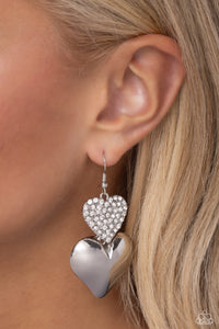 <p>Delicately dusted in white rhinestones, a blinding silver heart frame delicately links with a larger sleek silver heart for a flirtatiously layered look. Earring attaches to a standard fishhook earring.</p> <p><i> Sold as one pair of earrings.